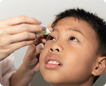 Kid applying atropine eye drops