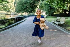 Child with no glasses holding a teddy bear