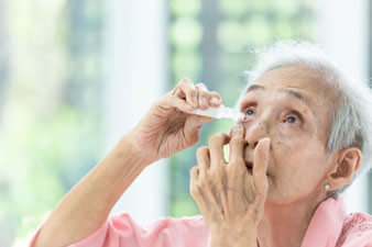 Asian senior woman putting eye drops for dry eyes