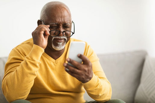Glaucoma patient wearing glasses looking at smartphone