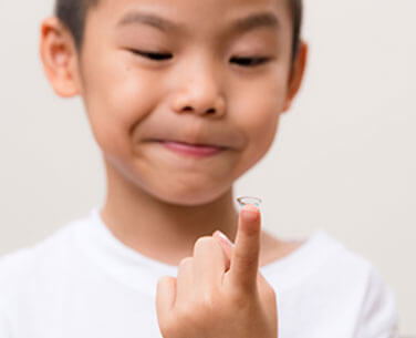 Kid holding contact lens on fingertips