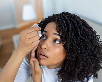 Woman curly hair applying eye drops