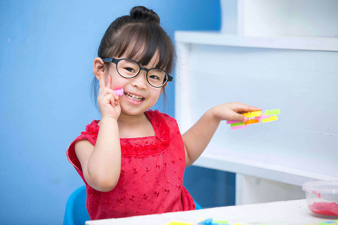 Little girl wearing glasses playing with legos